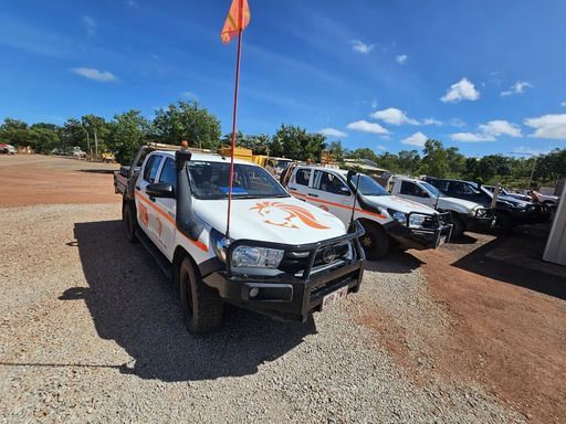 White Work Trucks Parked on A Gravel Lot Under a Blue Sky — Projected Contracting Electrical Services In Portsmith, QLD
