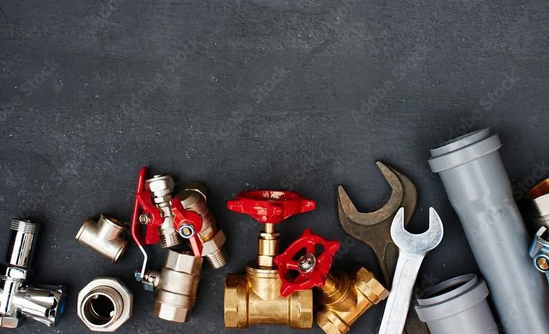 Assorted plumbing tools, pipes, and fittings on a dark background