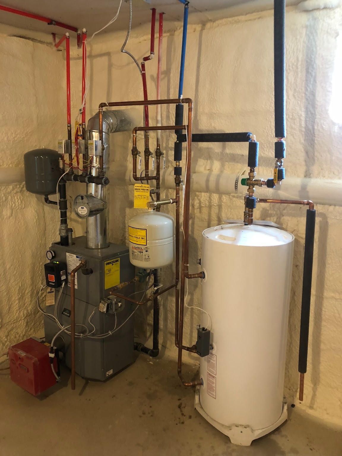 Basement mechanical room with pipes, boiler equipment, and a white water heater tank