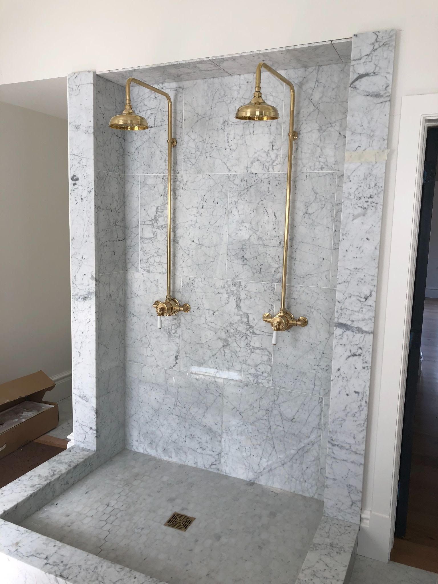 Hands installing a chrome shower fixture on a white tiled bathroom wall