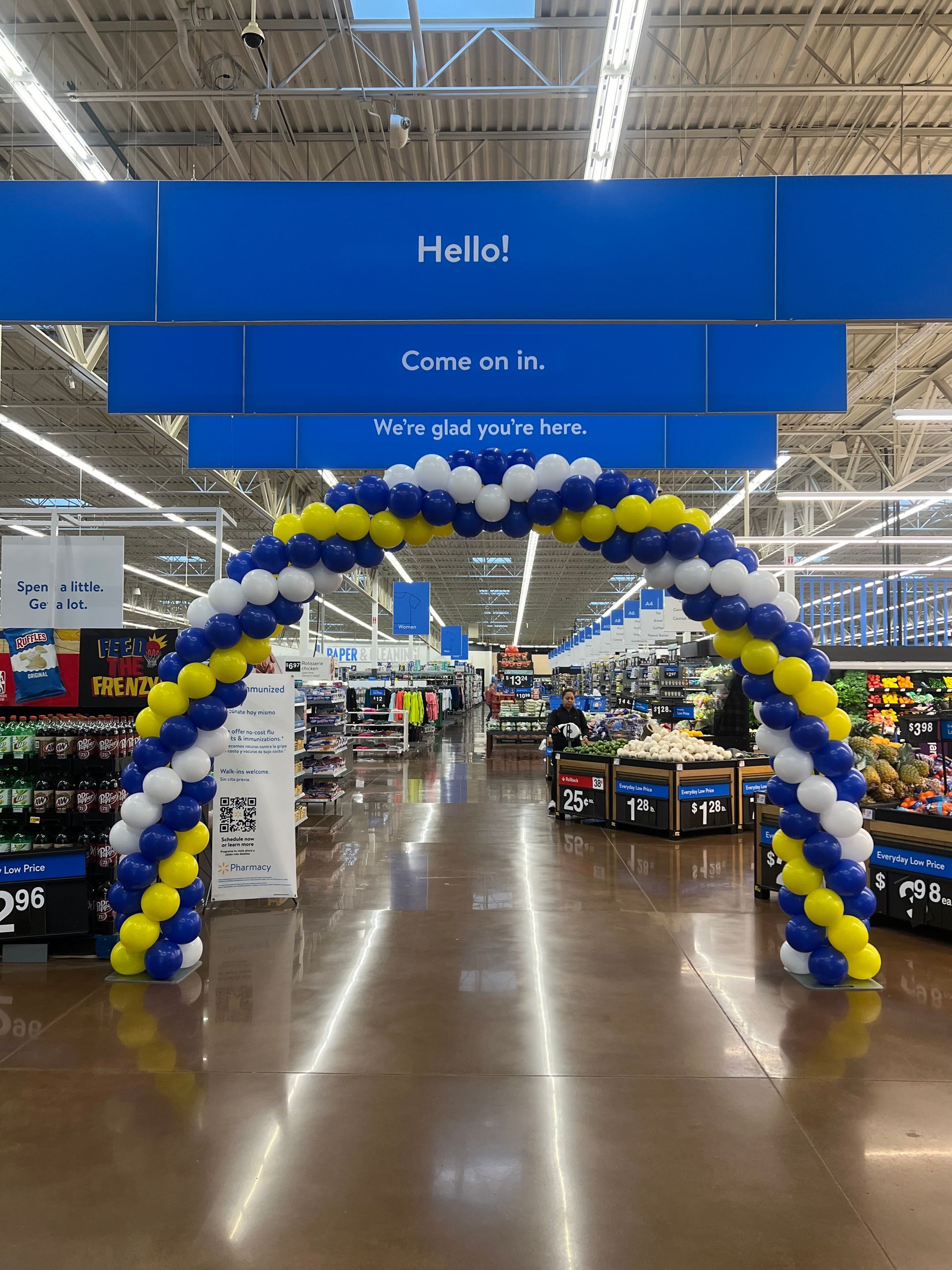 A blue and yellow balloon arch in a grocery store.
