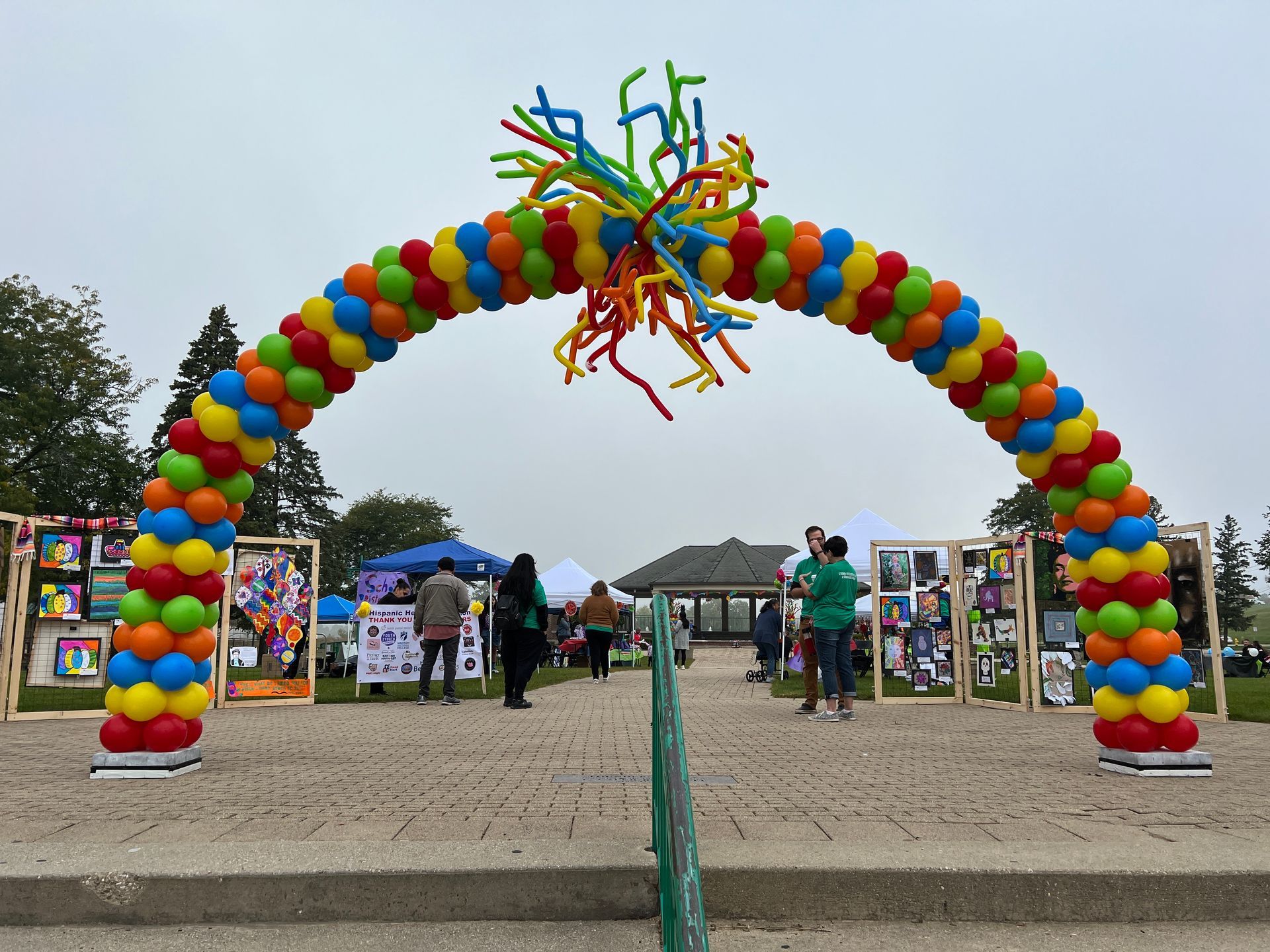 A large colorful balloon arch is surrounded by people