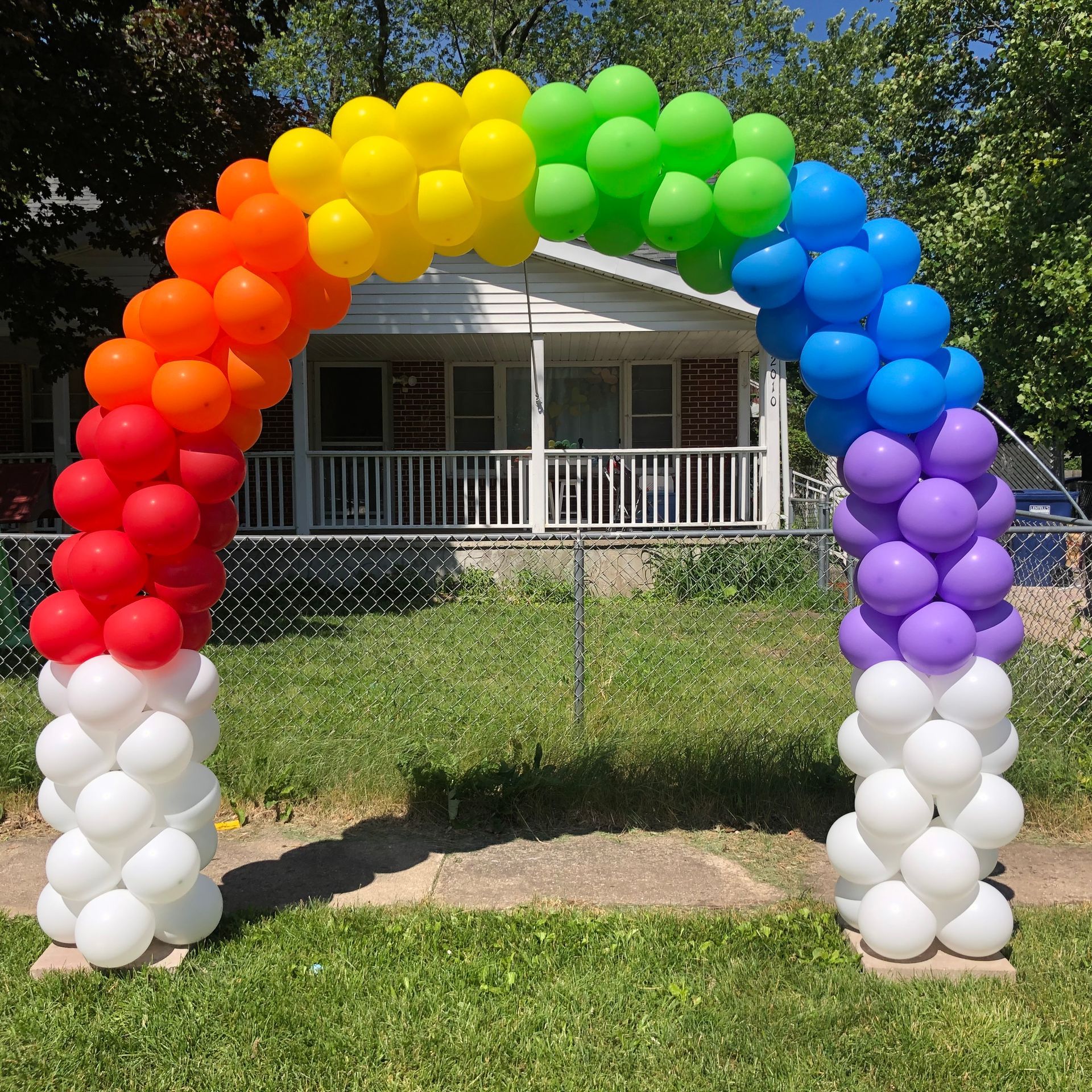 A rainbow colored balloon arch in front of a house