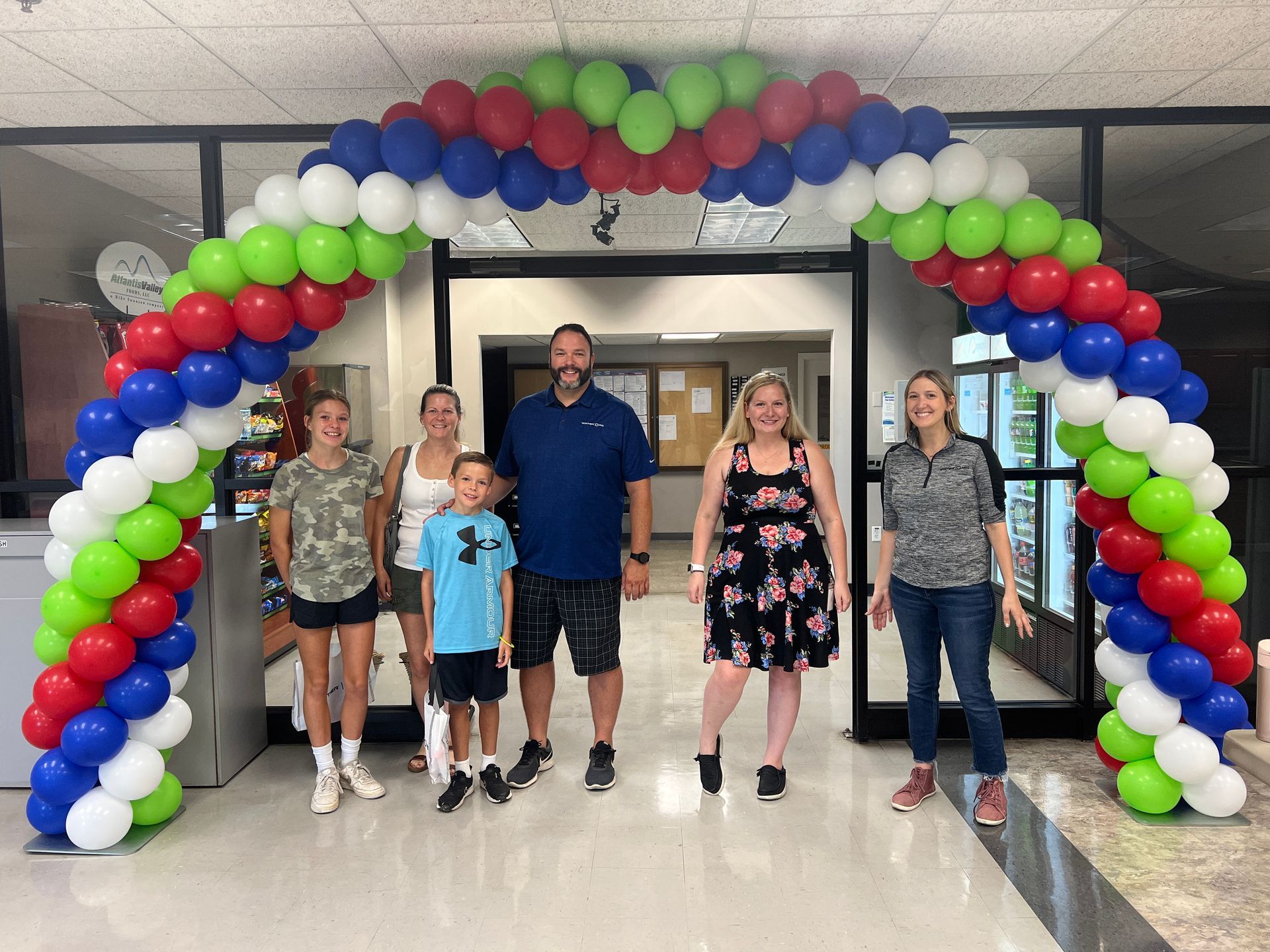 A group of people are standing under a balloon arch.