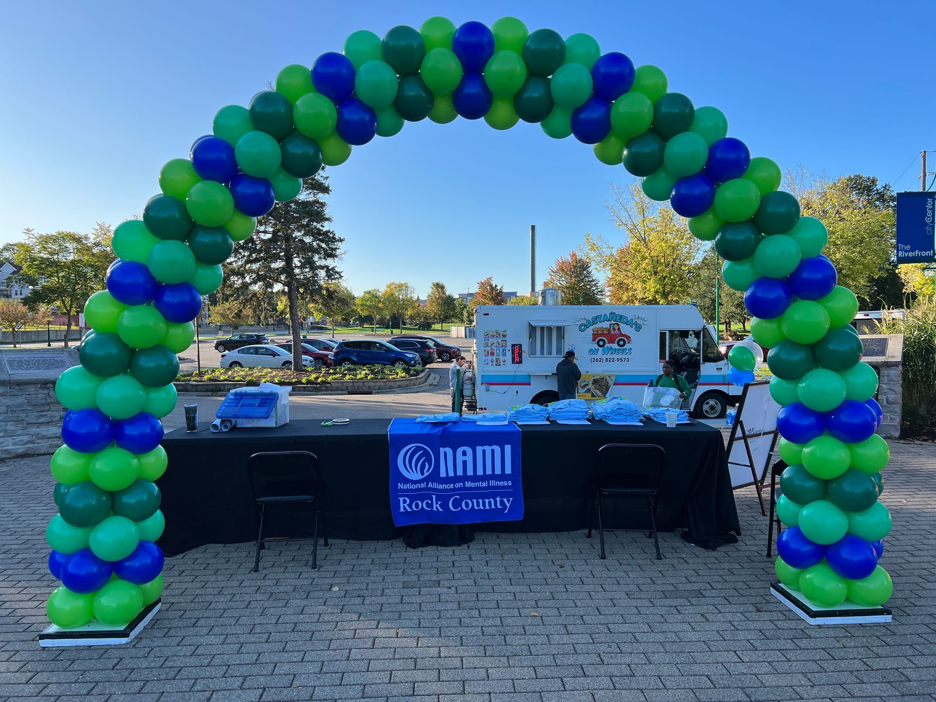 A green and blue balloon arch is surrounding a table.