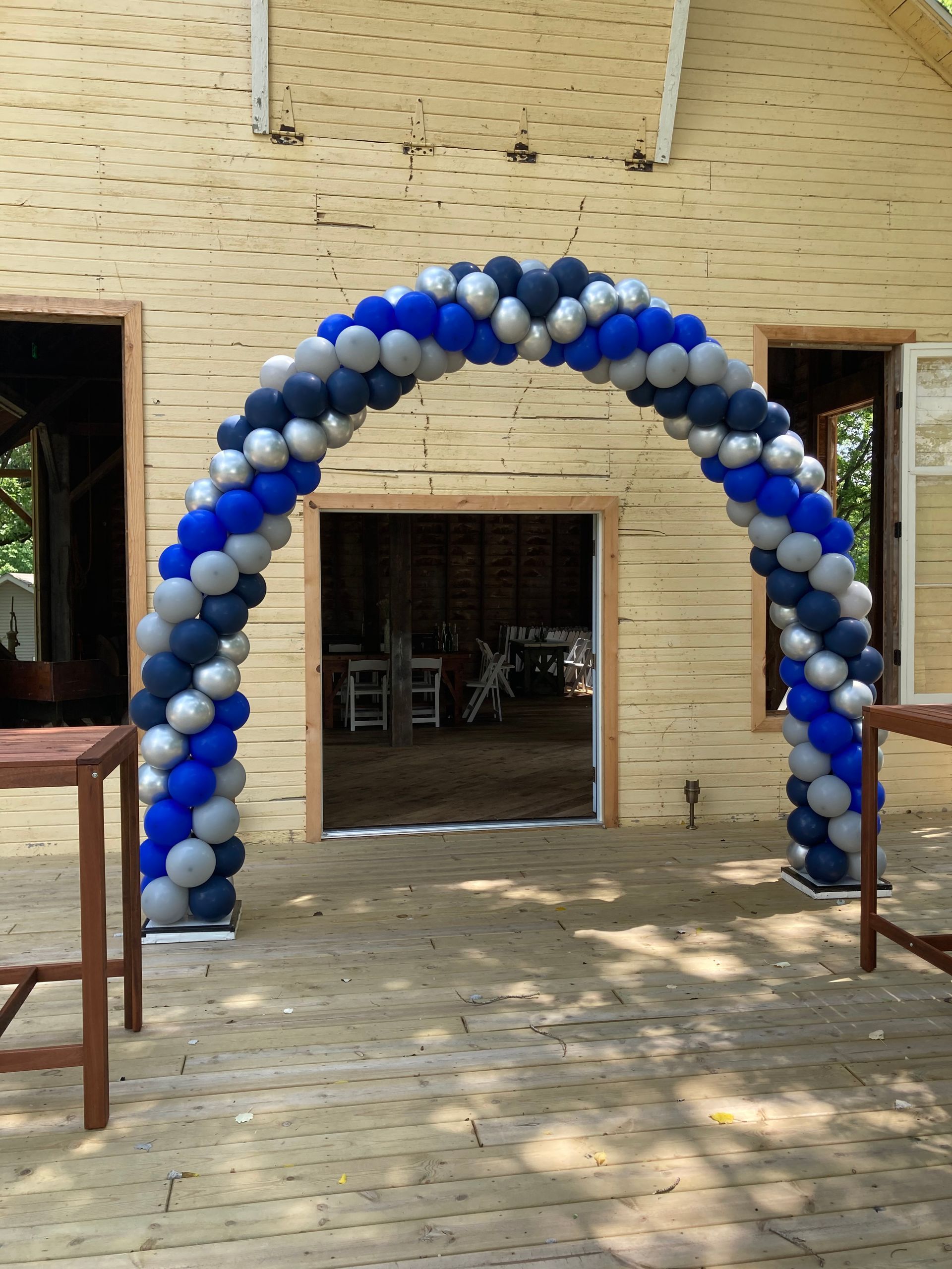A blue and silver balloon arch in front of a building