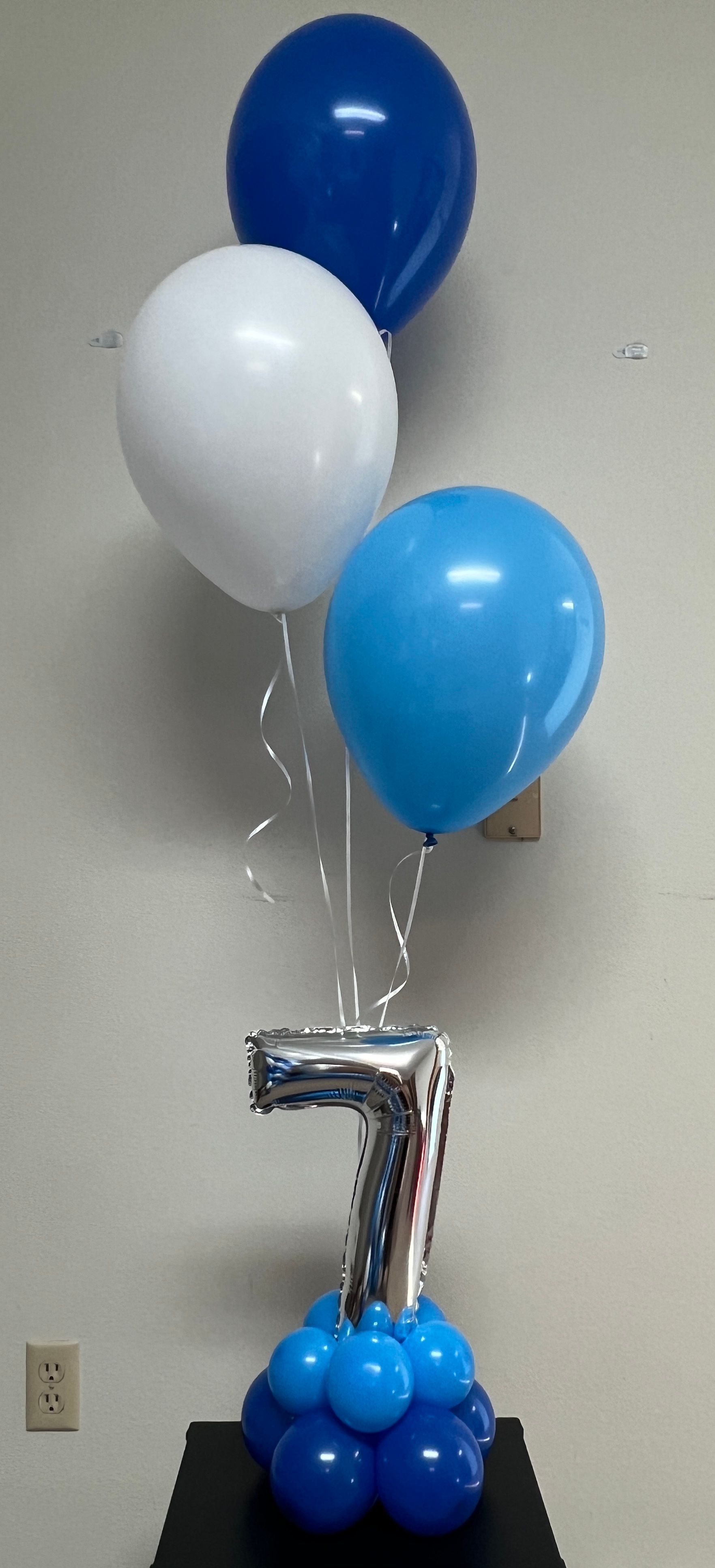 A bunch of blue and white balloons are sitting on a table.