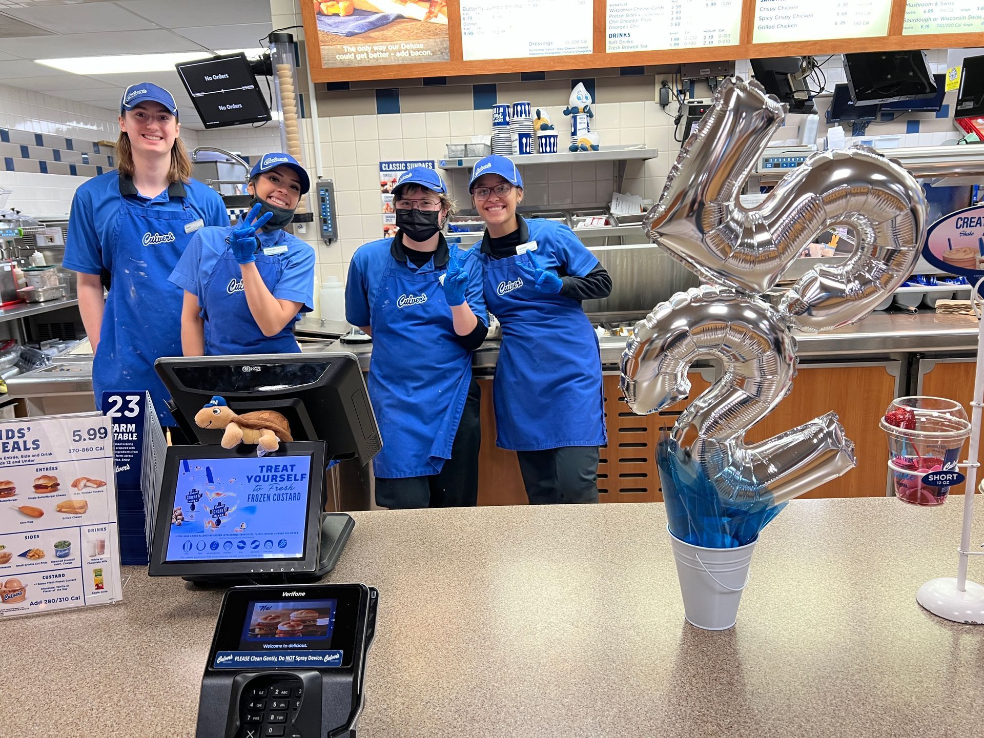 A group of people standing behind a counter in a fast food restaurant.