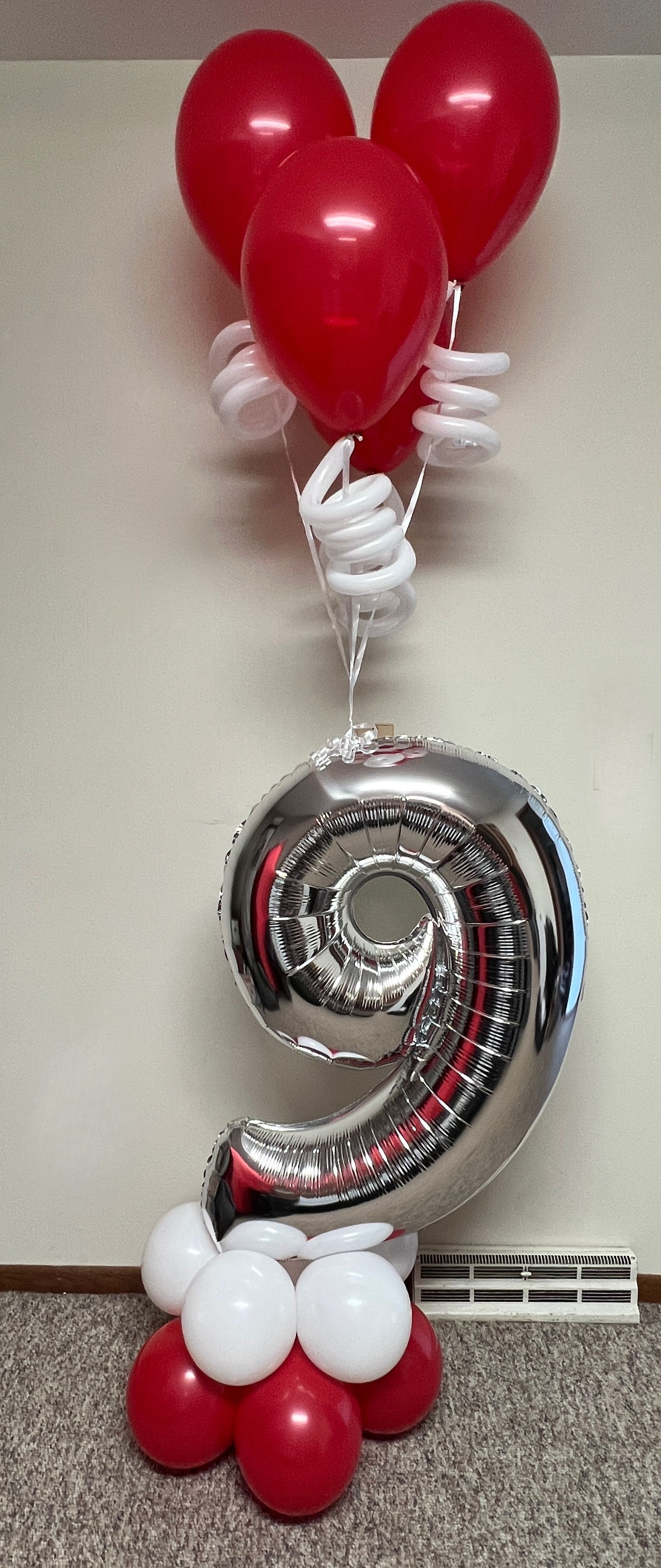 A bunch of red and white balloons sitting on top of a number 9 balloon.