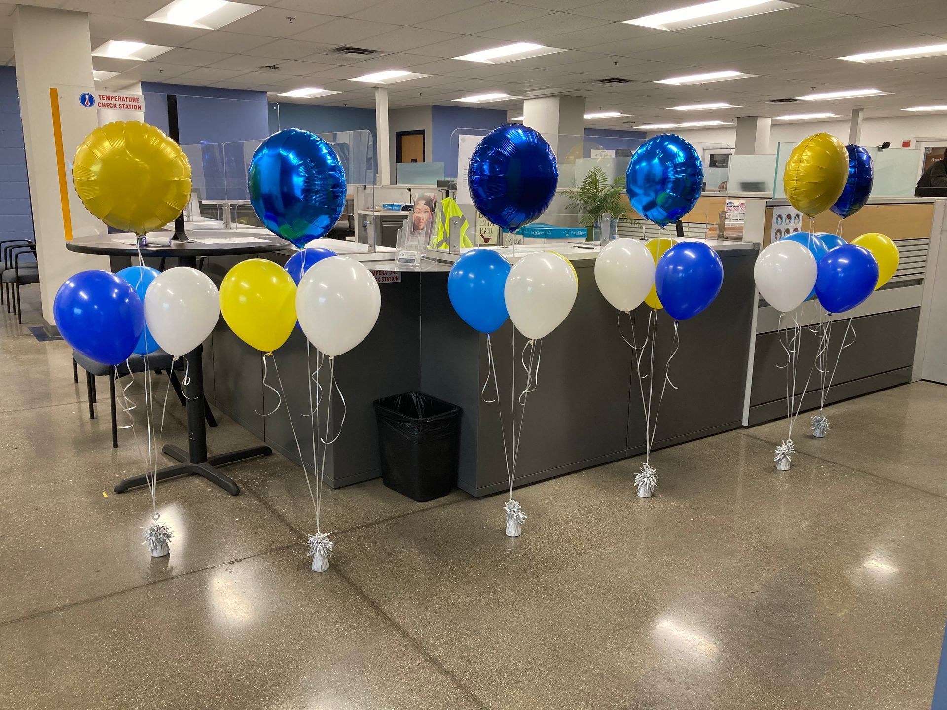 A bunch of balloons are sitting on the floor in an office