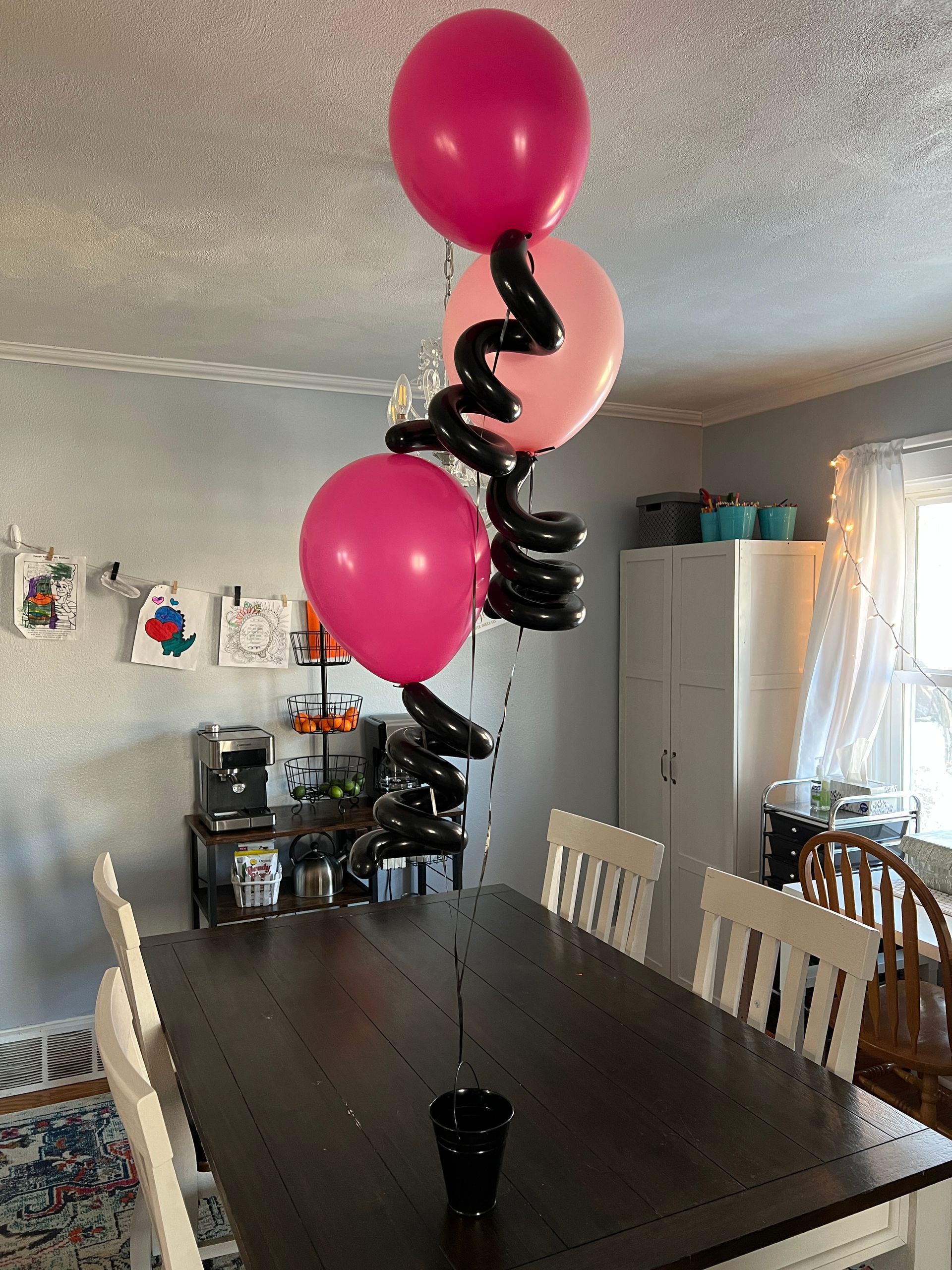A bunch of pink and black balloons are sitting on top of a wooden table.