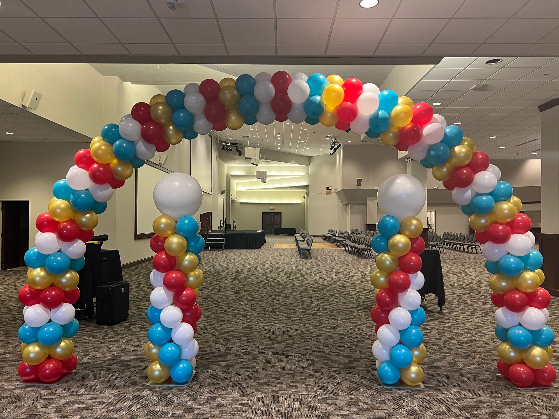 A large arch made of red , white , and blue balloons in a room.
