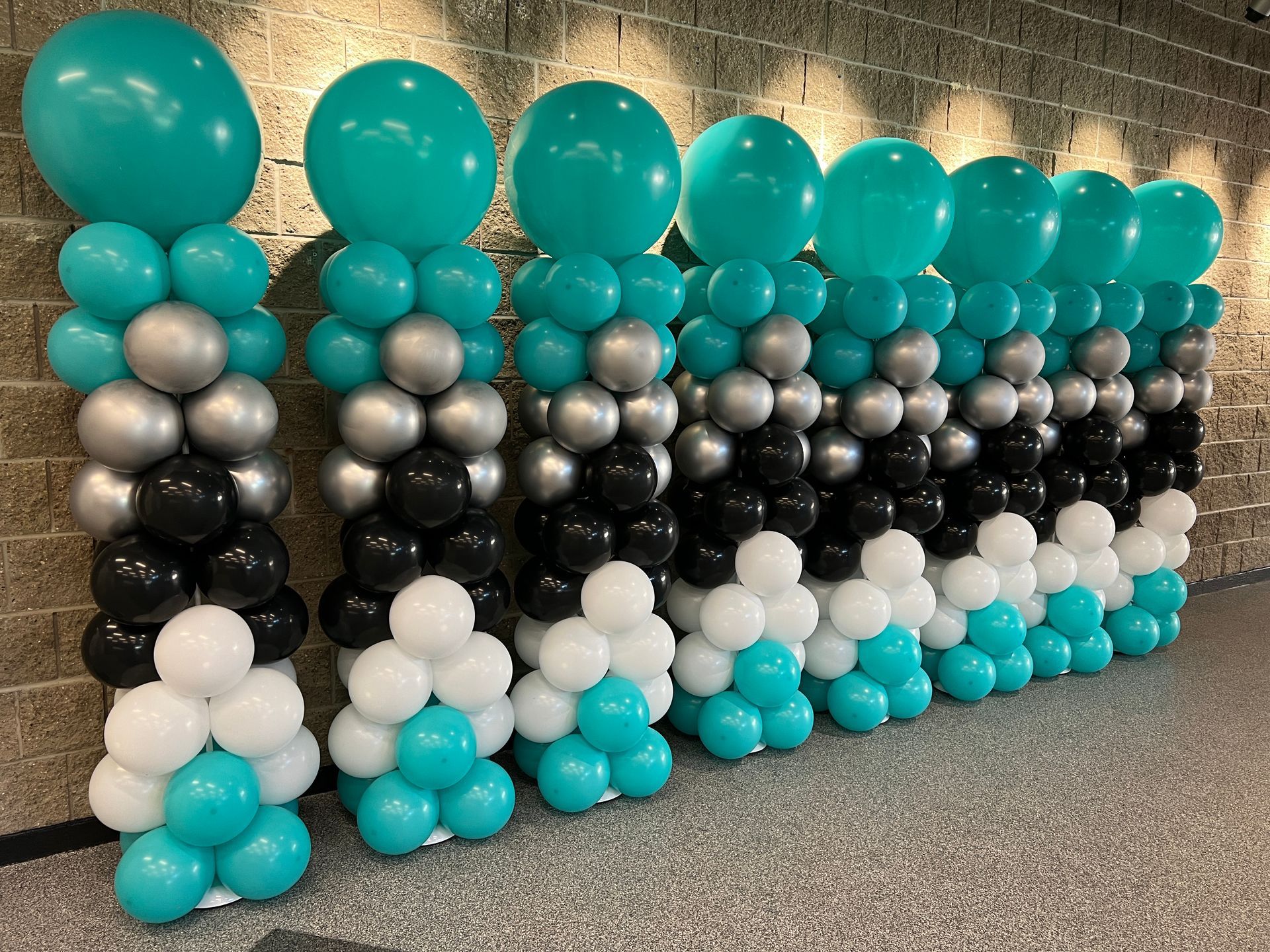 A row of balloons stacked on top of each other in front of a brick wall.