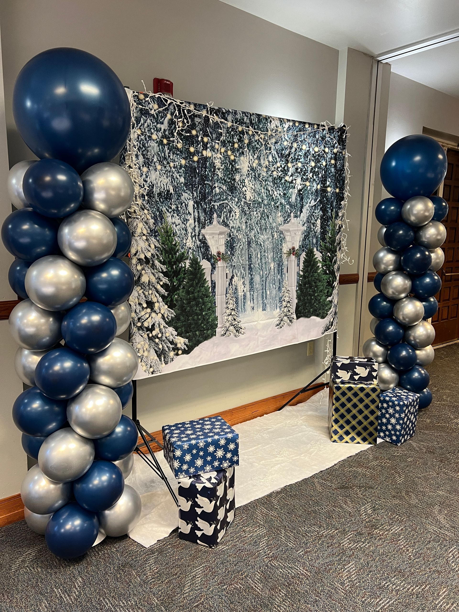 A room decorated with blue and silver balloons and a picture of a snowy forest.