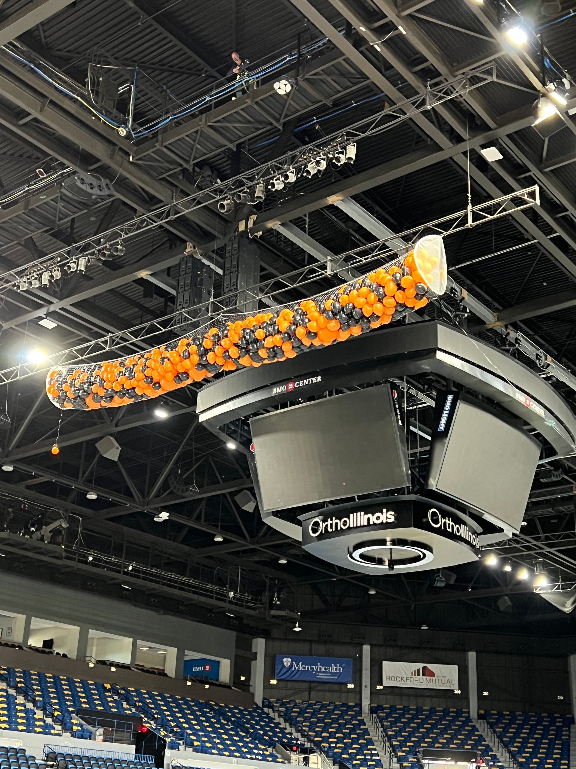 A large ceiling with balloons hanging from it in a stadium.