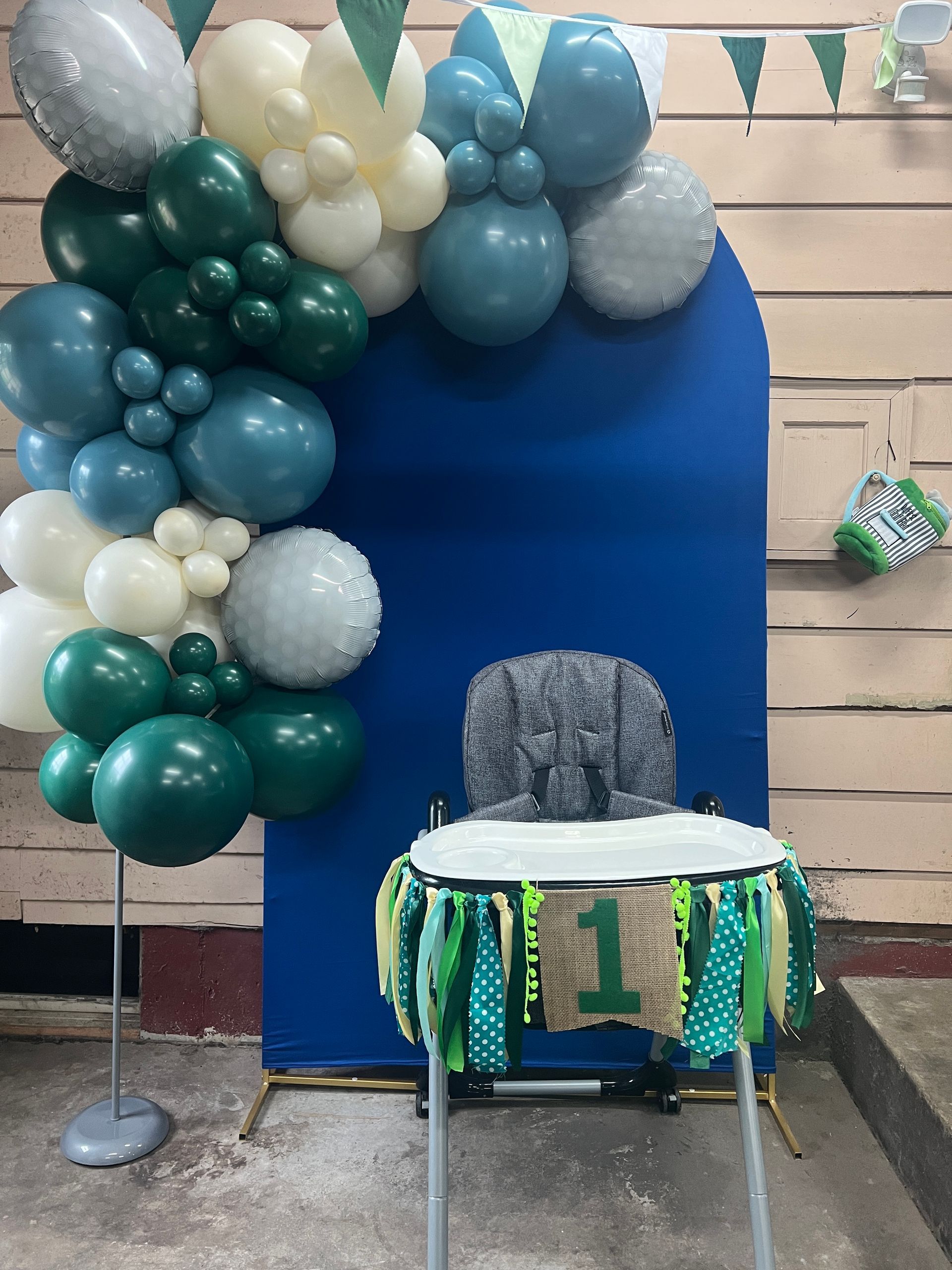 A high chair is decorated with balloons for a baby 's first birthday.