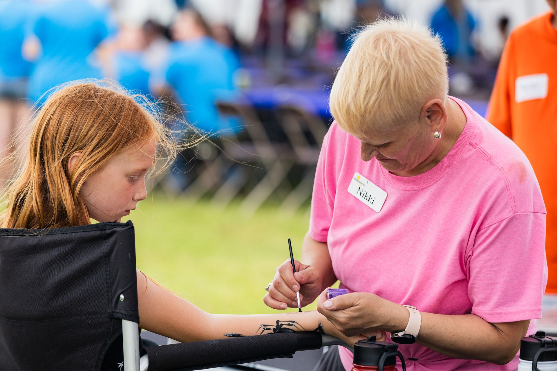 A woman is painting a girl 's arm with henna.