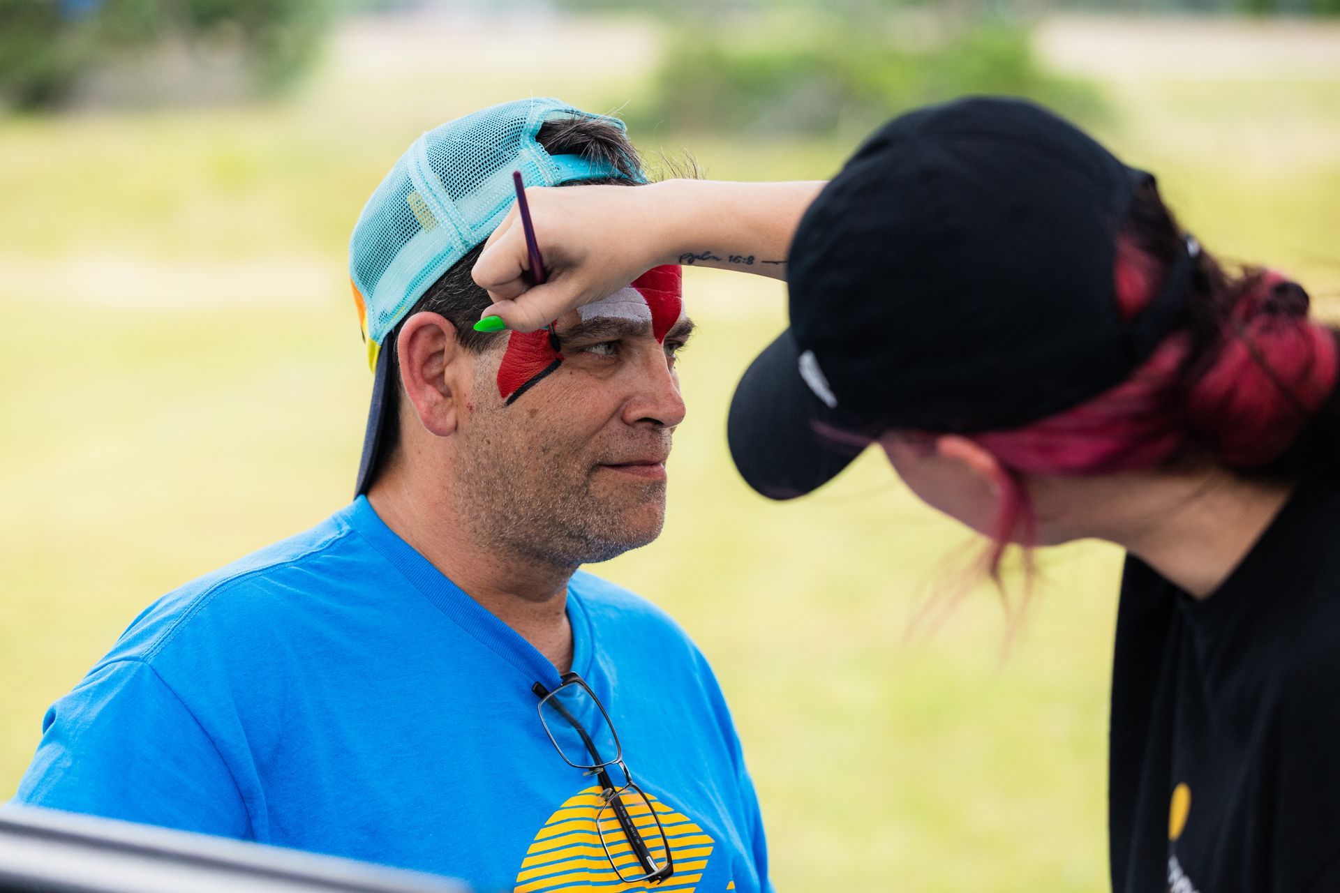 A man is getting his face painted by a woman.