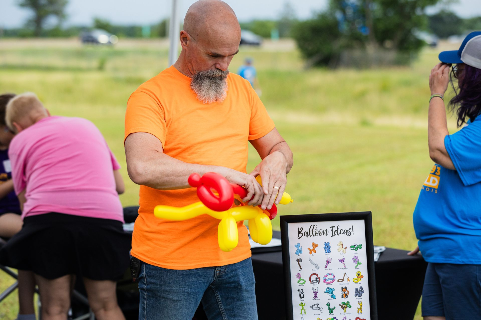 A man is making balloon animals at a park.