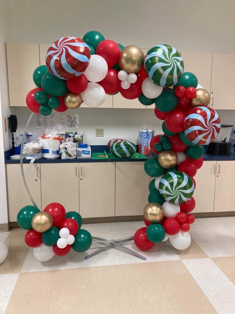 A christmas balloon arch is sitting on the floor in a kitchen.