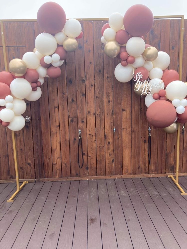 A wooden fence with balloons hanging from it.