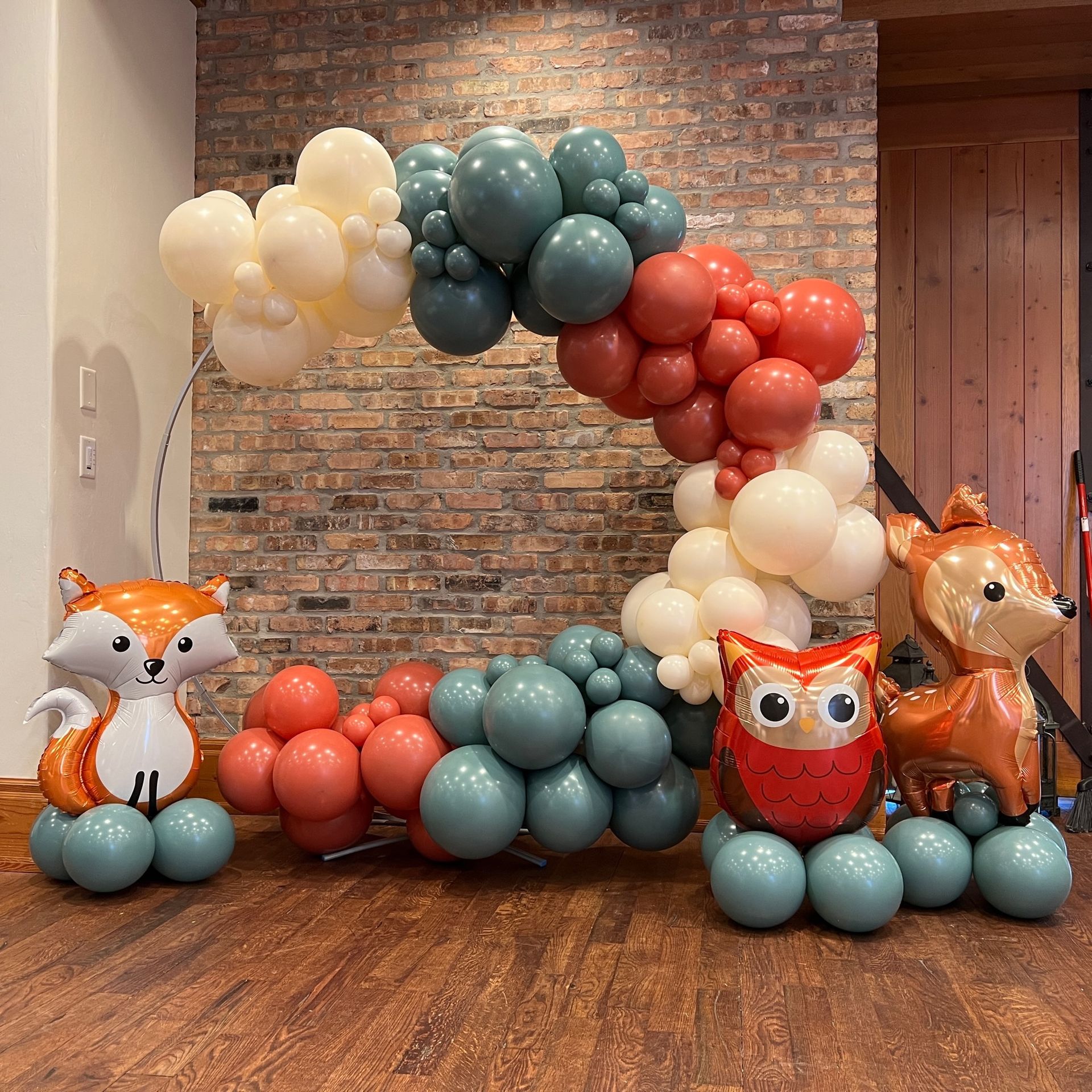 A bunch of balloons in the shape of animals are sitting on a wooden floor.