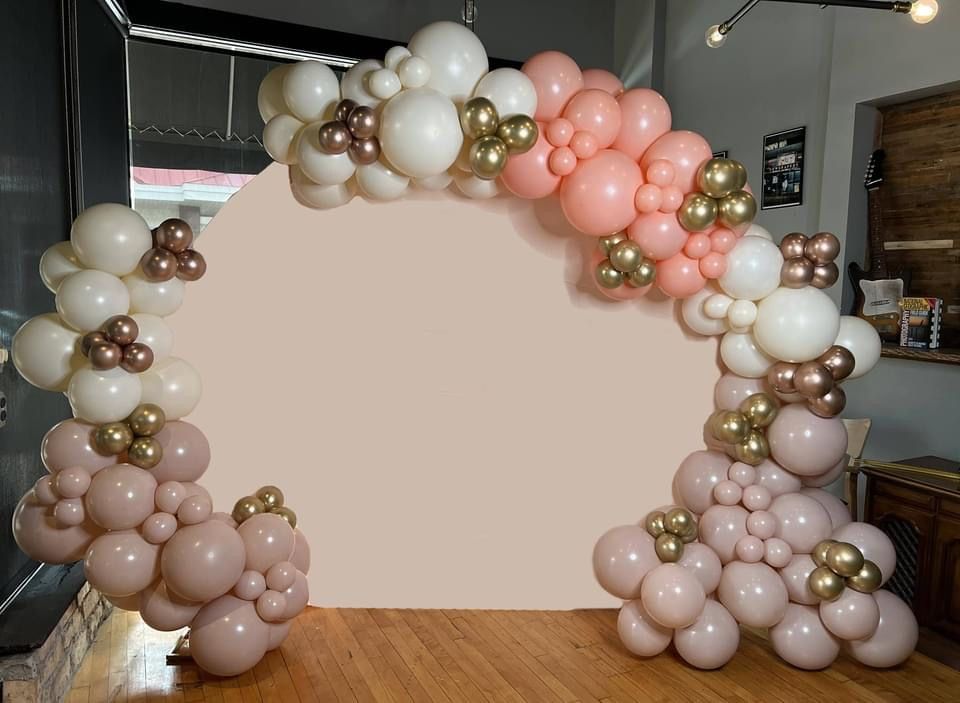 A bunch of balloons are sitting on a wooden floor in front of a wall.