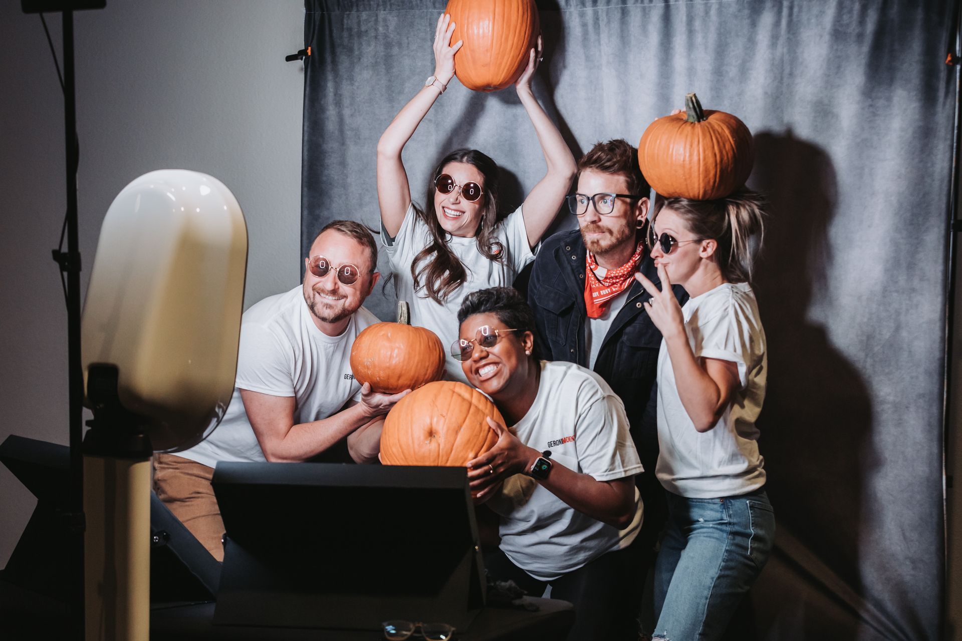 A group of people are posing for a picture with pumpkins.