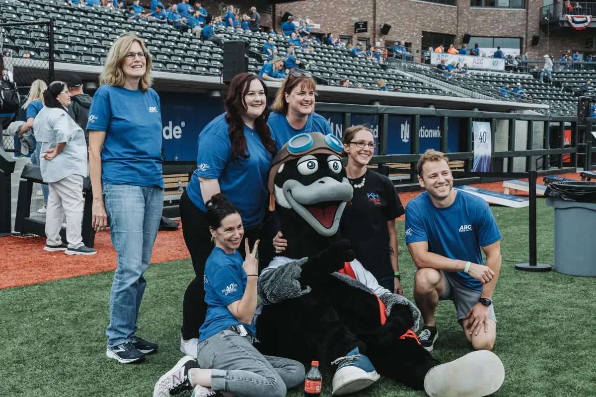 A group of people are posing for a picture with a mascot on a baseball field.