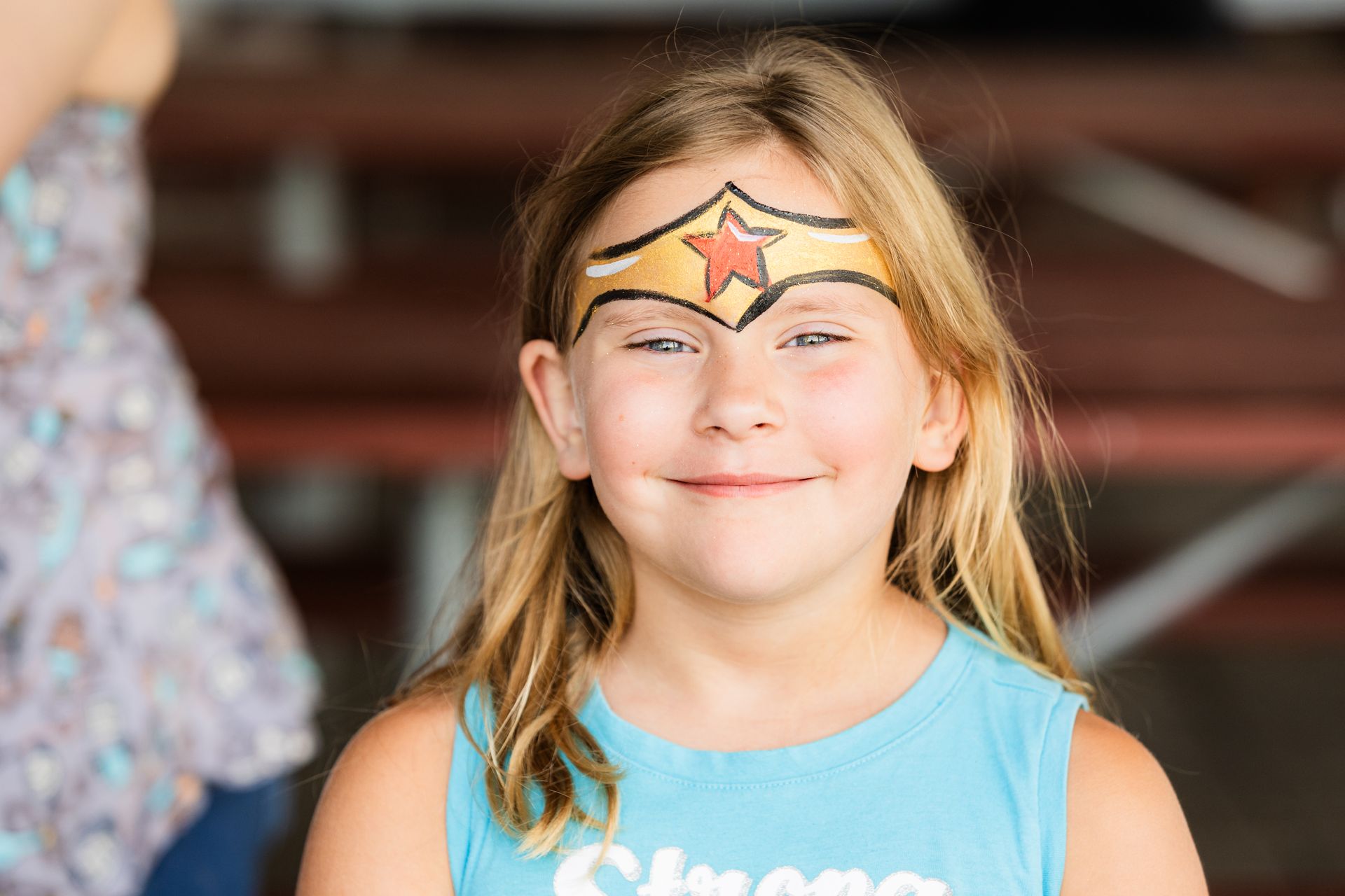 A young girl with wonder woman painted on her face.