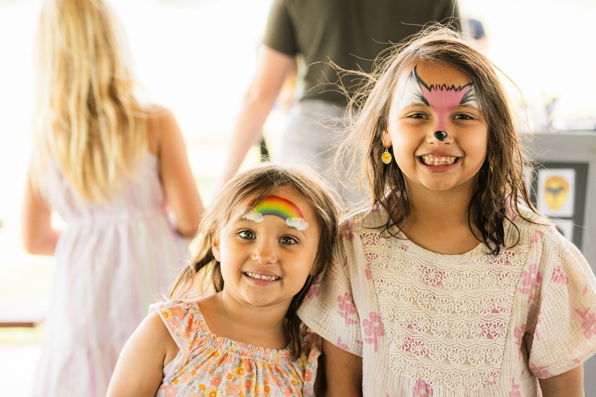 Two little girls with face paint on their faces are posing for a picture.