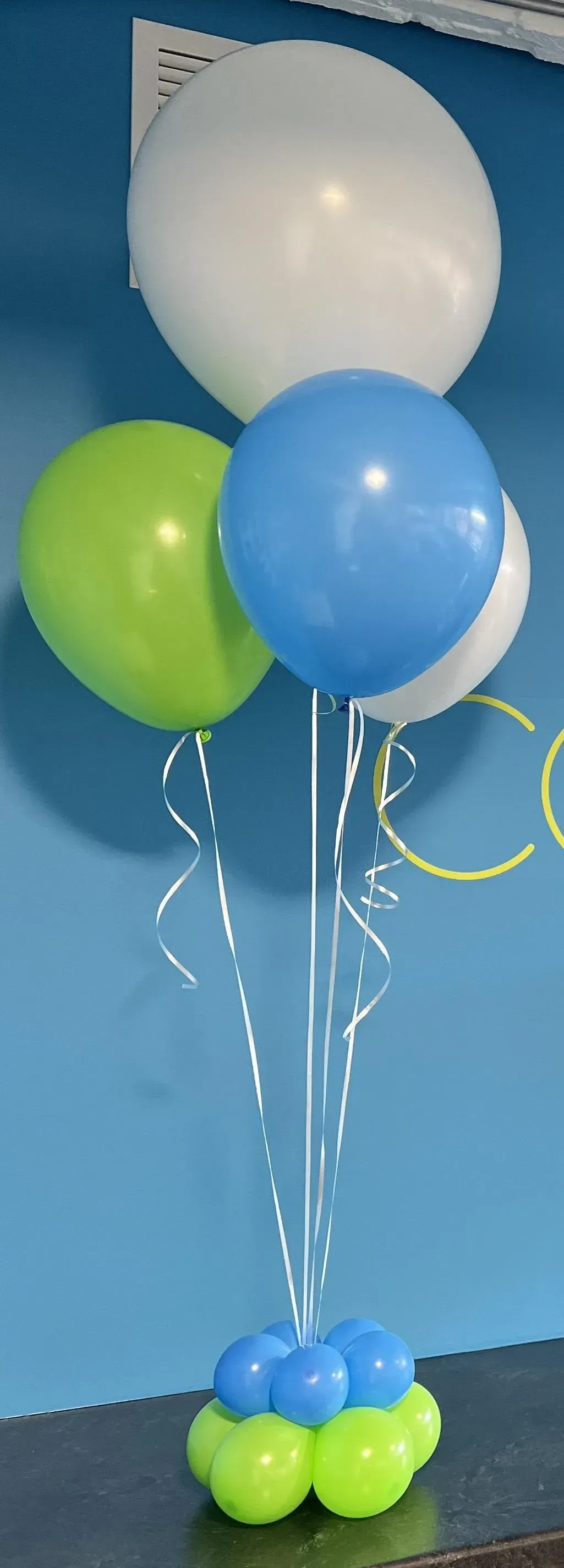 A bunch of balloons are sitting on a table in front of a blue wall.