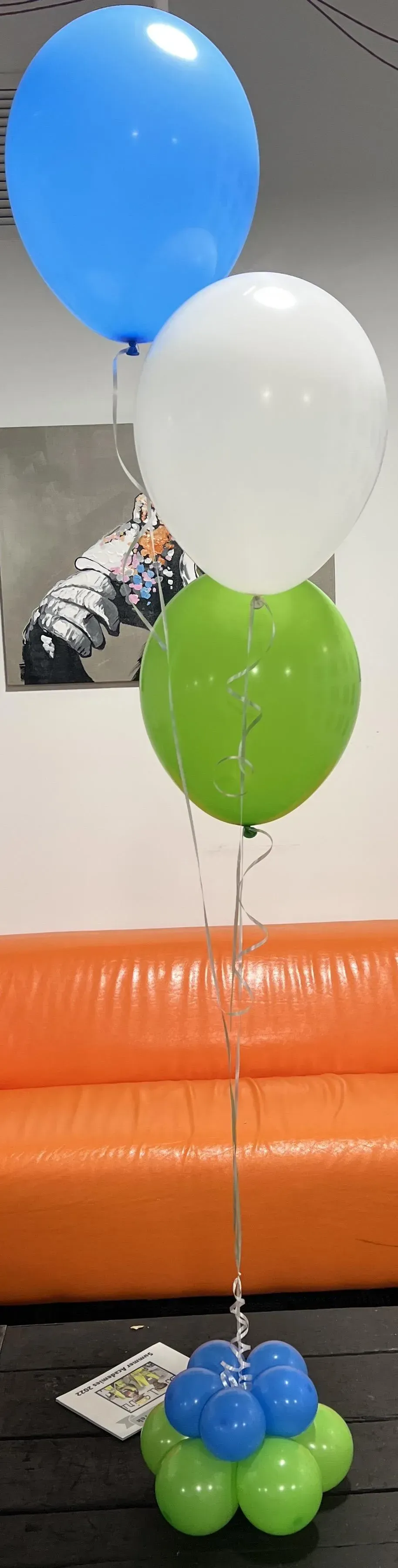 A bunch of balloons are sitting on a table in front of an orange couch.