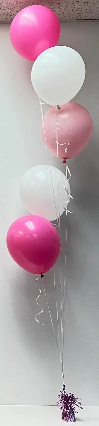 A bunch of pink and white balloons hanging from the ceiling.
