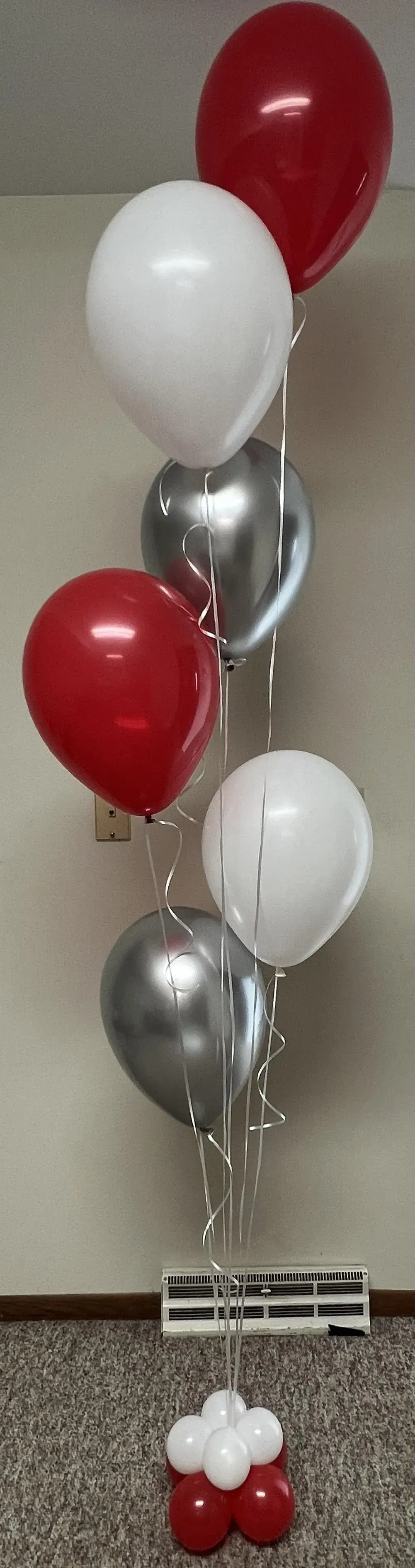 A bunch of red , white and silver balloons hanging from the ceiling.