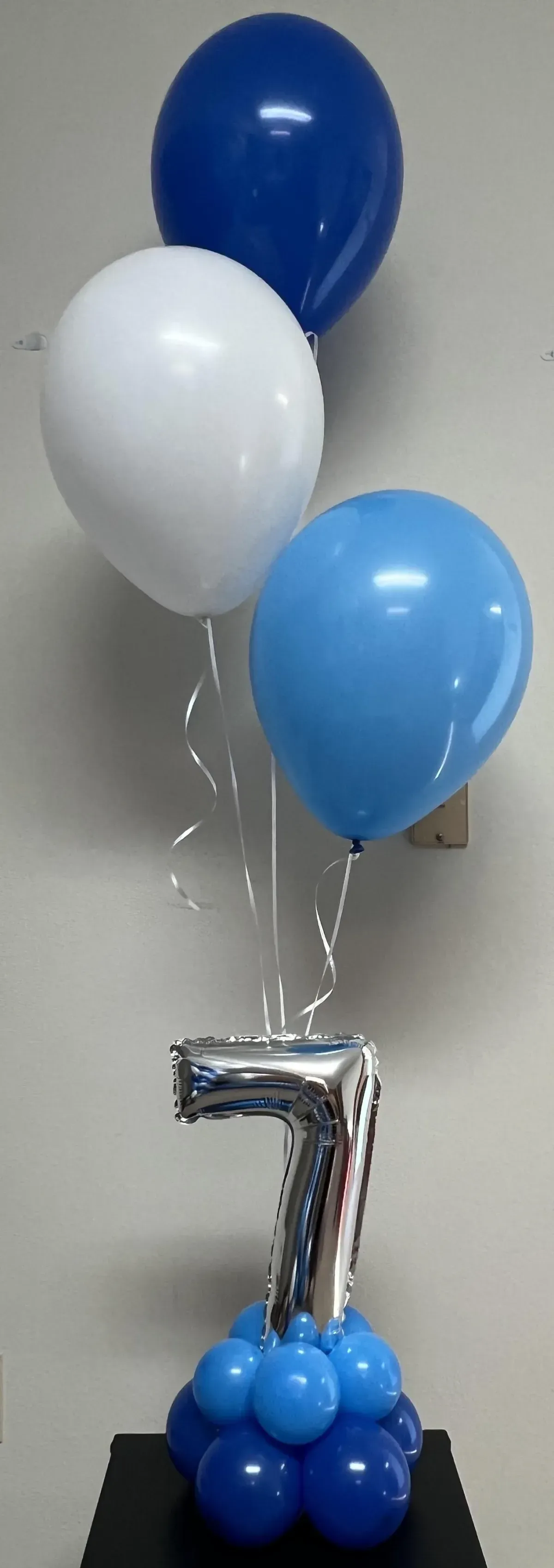 A bunch of blue and white balloons with a number 7 on top of them.
