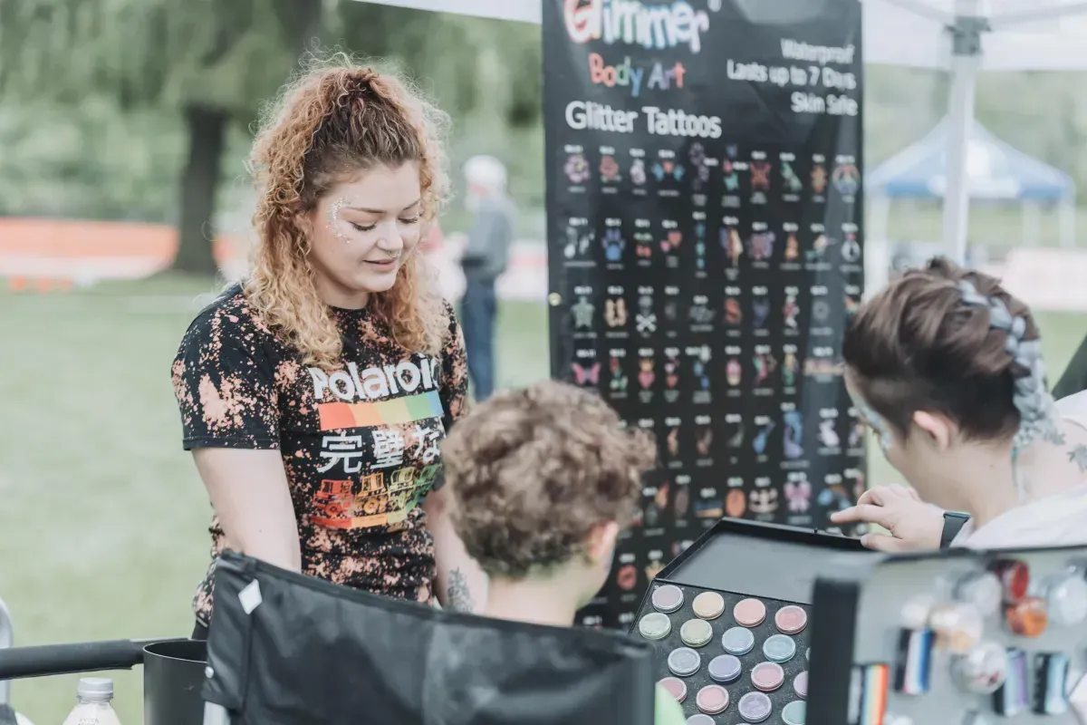 A woman is standing in front of a sign that says body art.