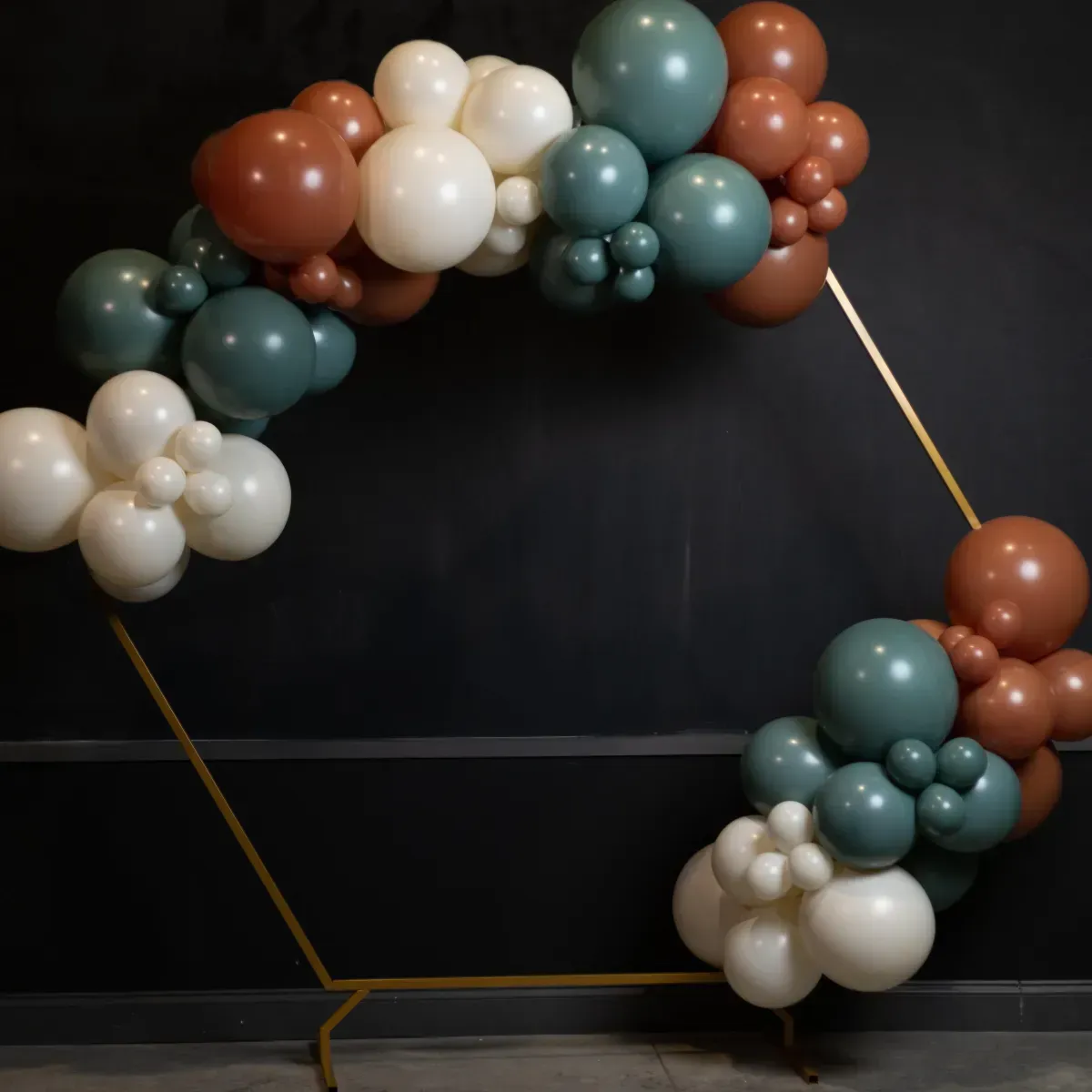 A balloon arch is sitting in front of a black wall.