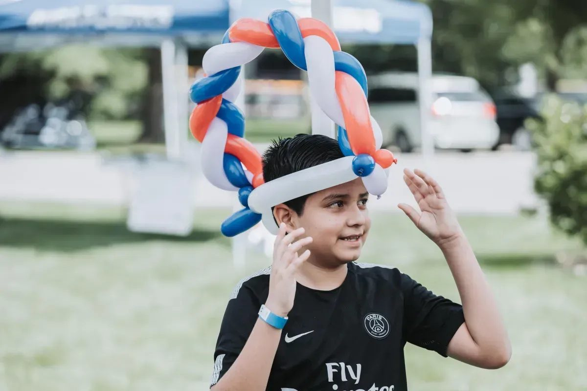 A young boy wearing a hat made of balloons.