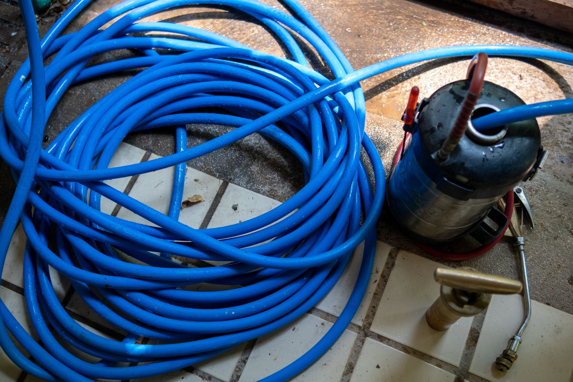 A blue hose is laying on a tiled floor next to a fire extinguisher