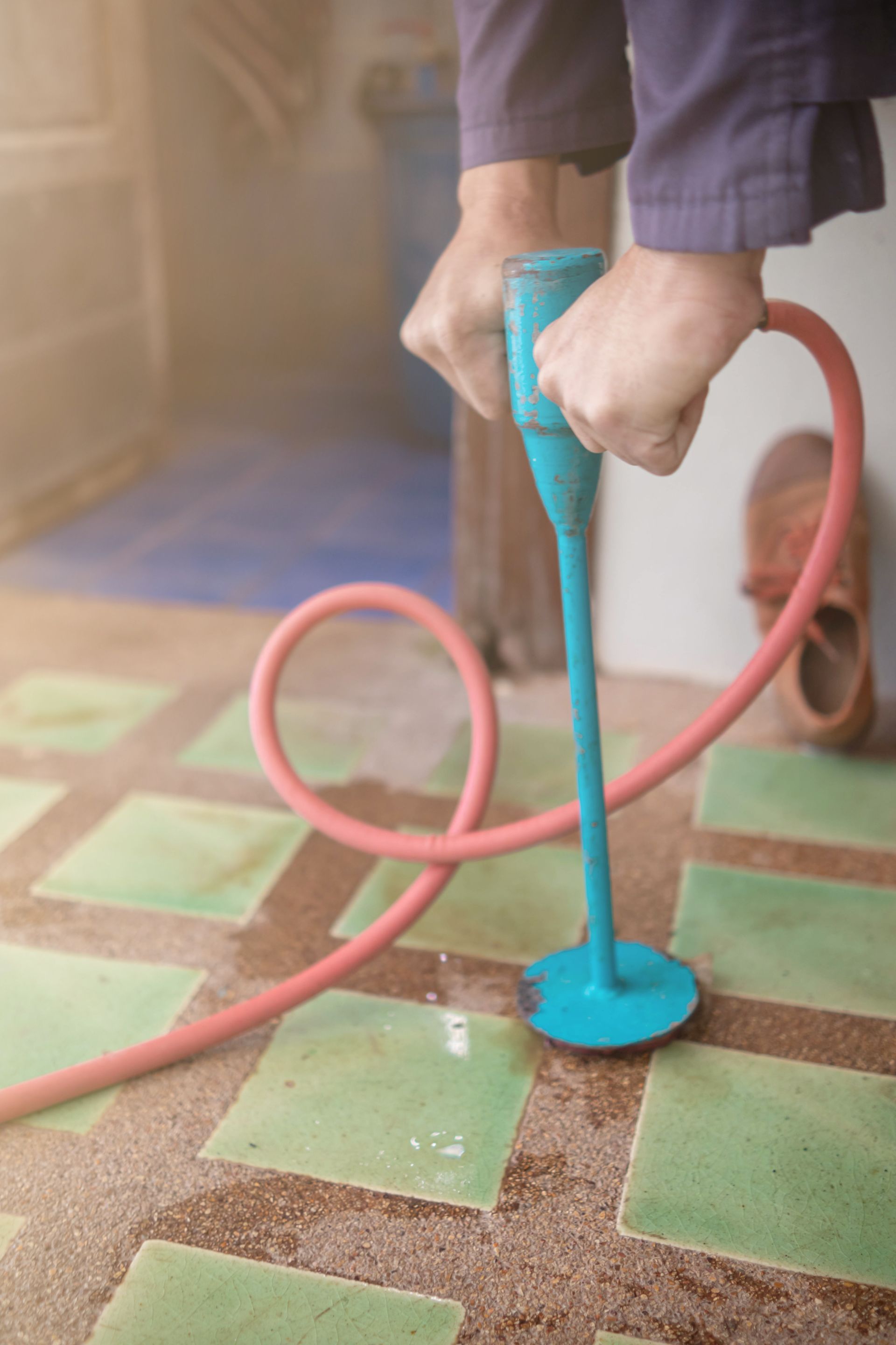 A person is holding a blue object with a pink hose attached to it.