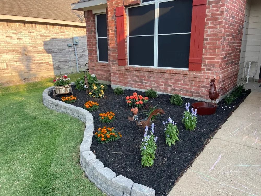 Brick house with a landscaped flowerbed and black mulch.