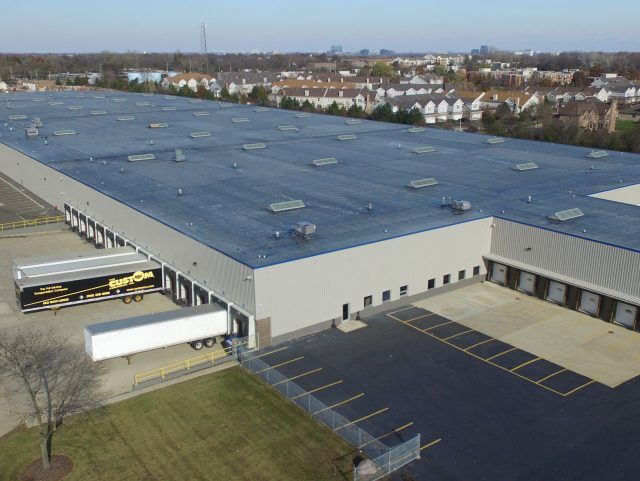 An aerial view of a large warehouse with trucks parked in front of it.