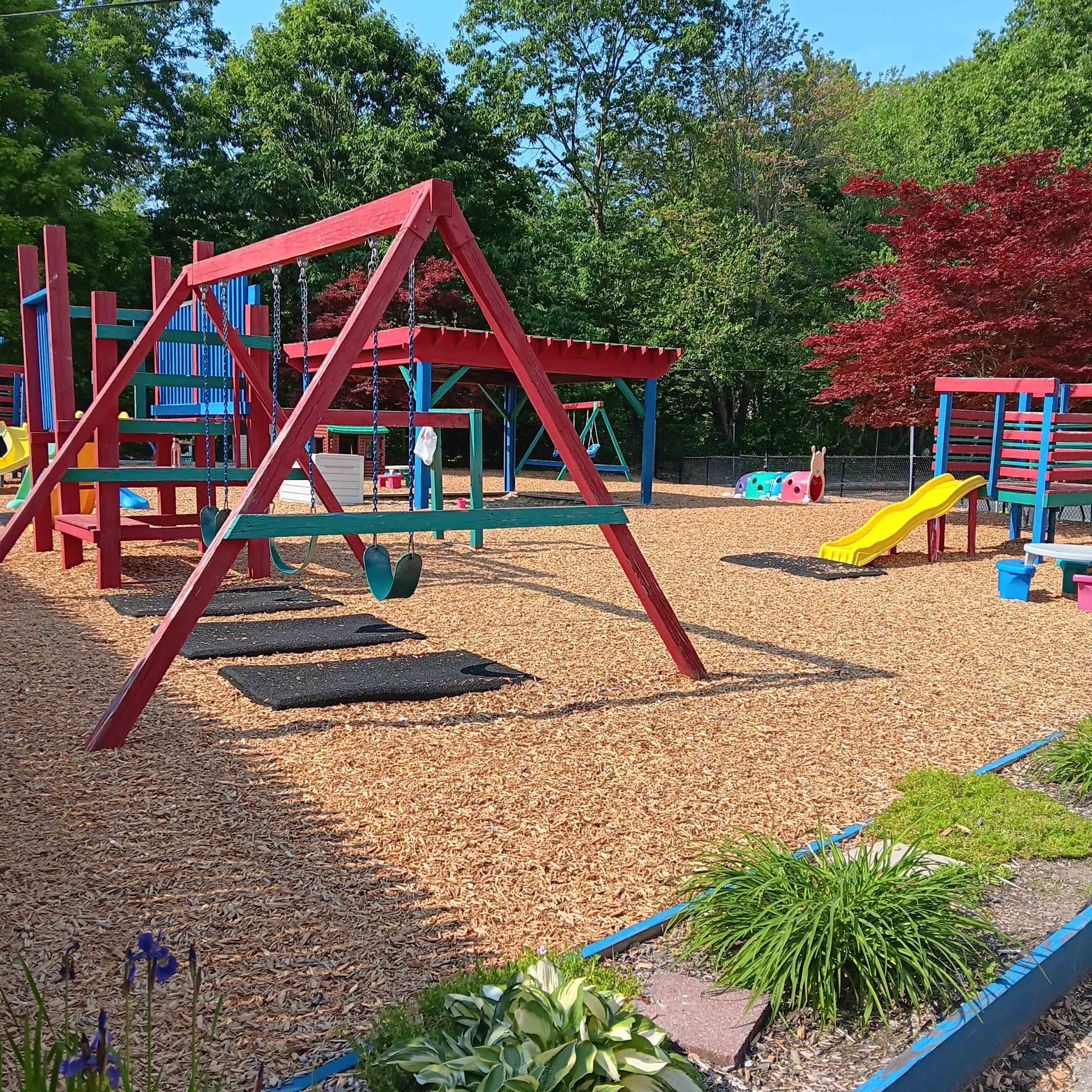 A playground with a red swing set and a yellow slide.