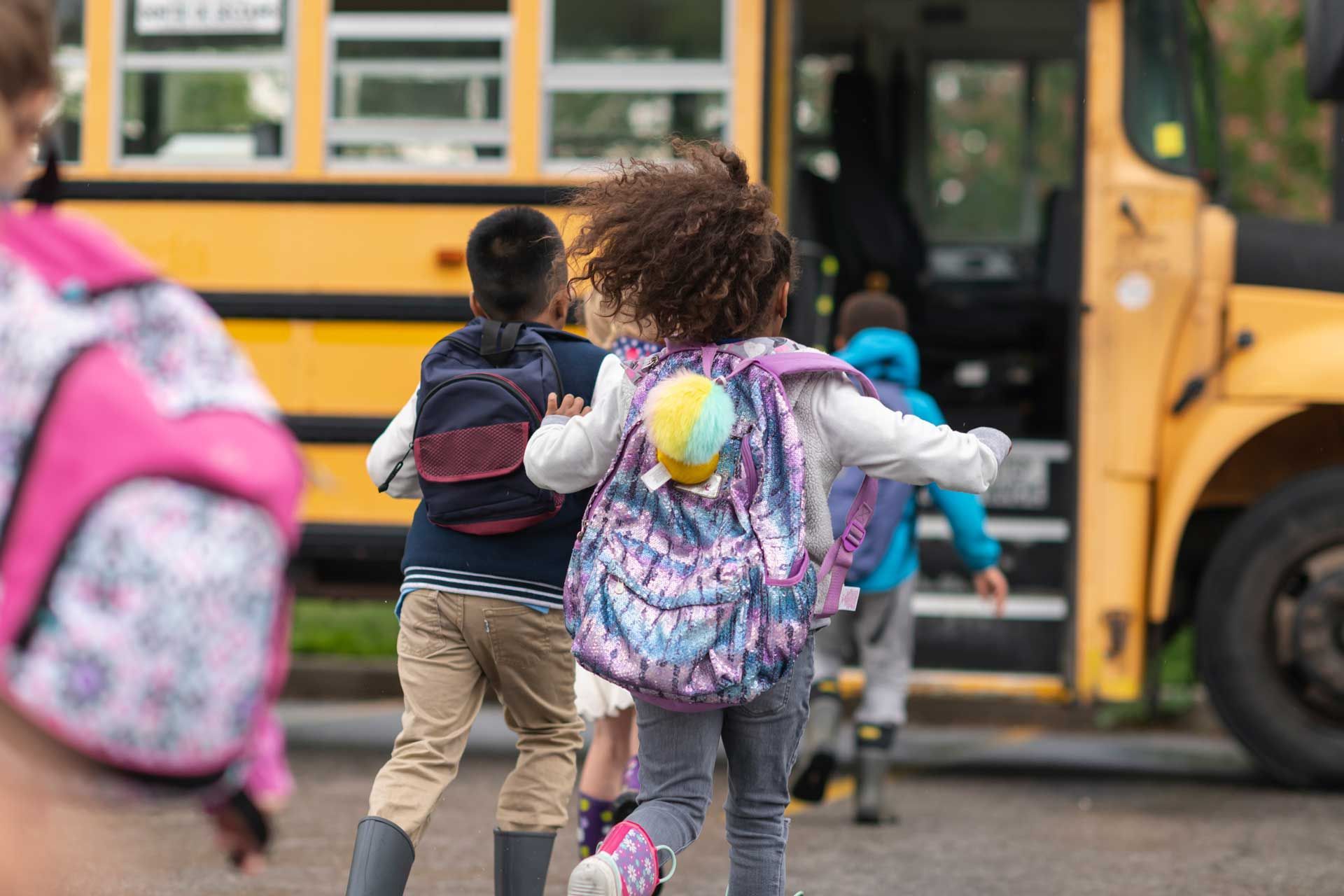 A group of children are running towards a school bus.