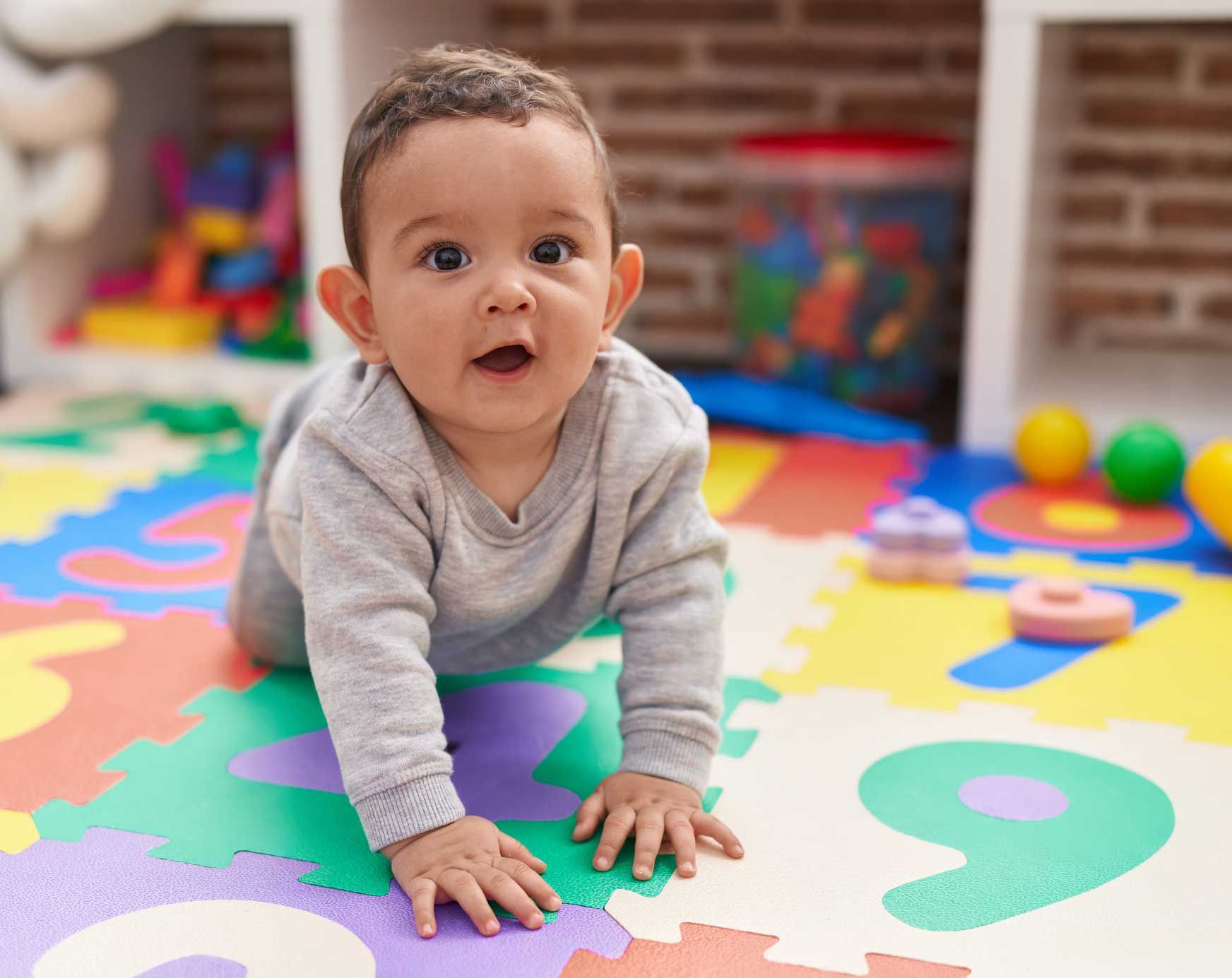 A baby is crawling on a colorful puzzle mat.