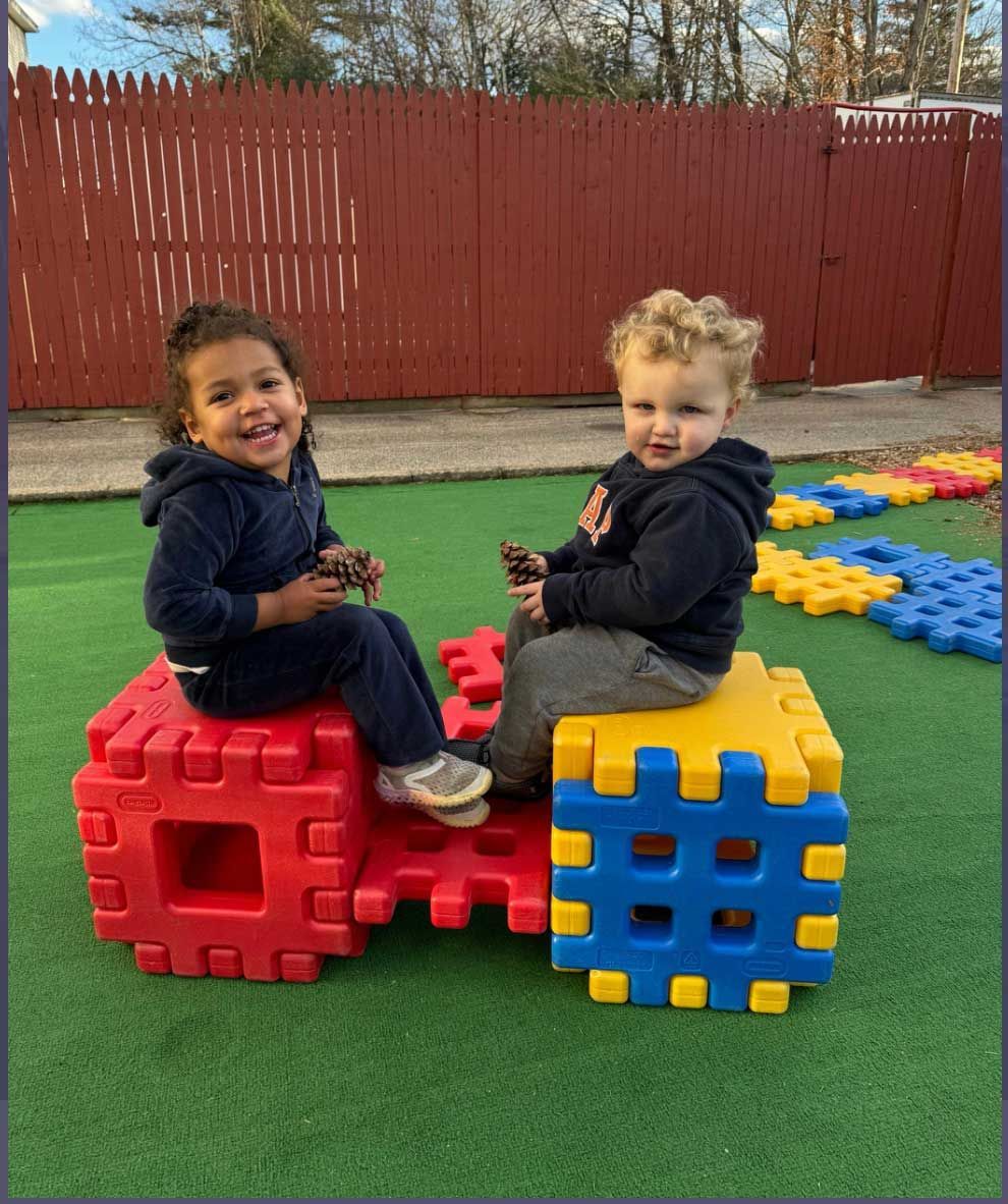 A boy and a girl are sitting on blocks in a playground.