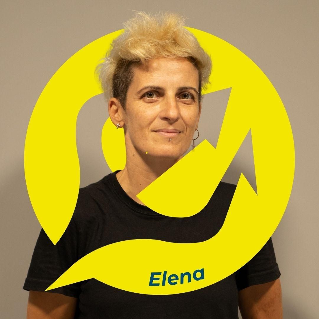 Elena con i capelli biondi corti davanti a un logo giallo. Indossa una maglietta nera.