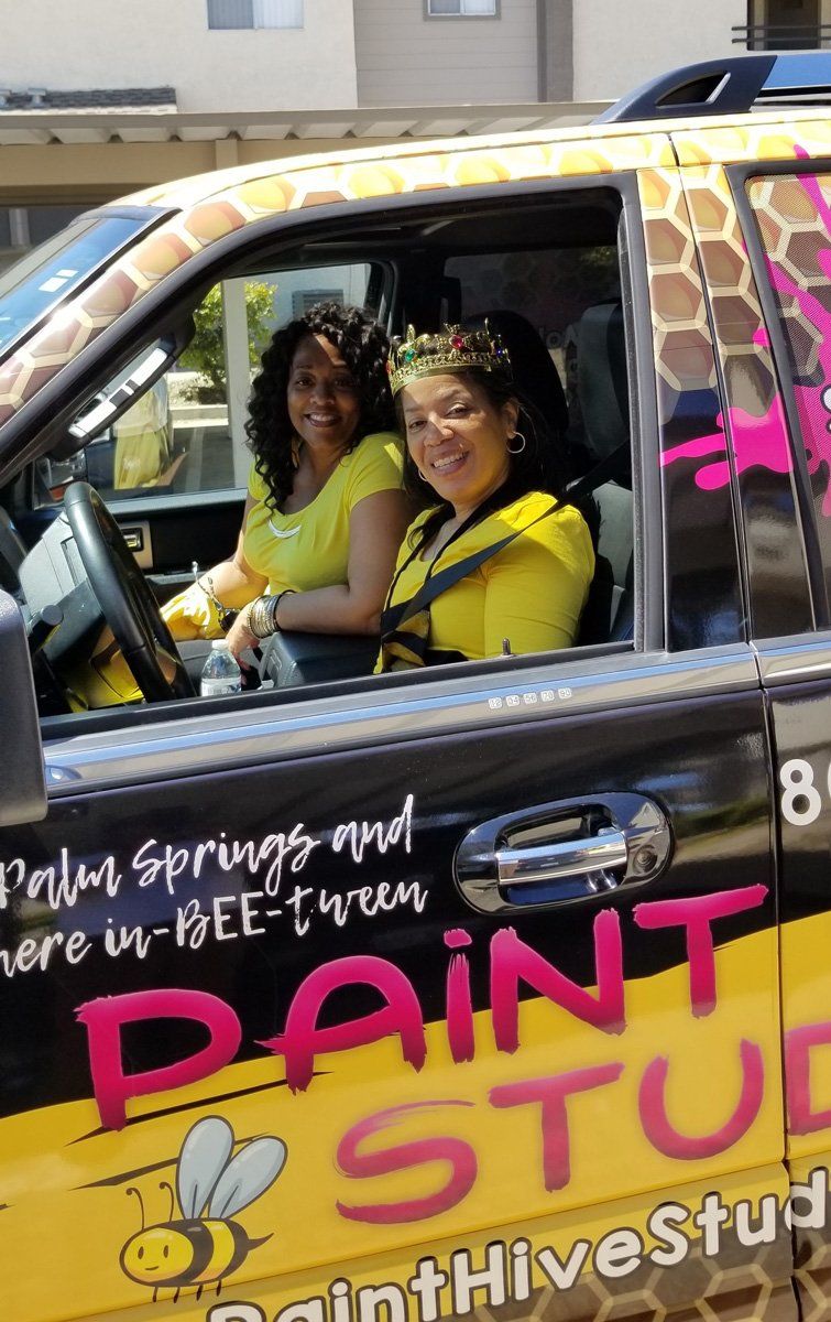 Two women in yellow shirts in a car with 