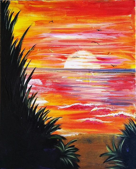 Sunset over water with palm fronds. Vibrant orange, yellow, and red sky reflecting in the ocean.